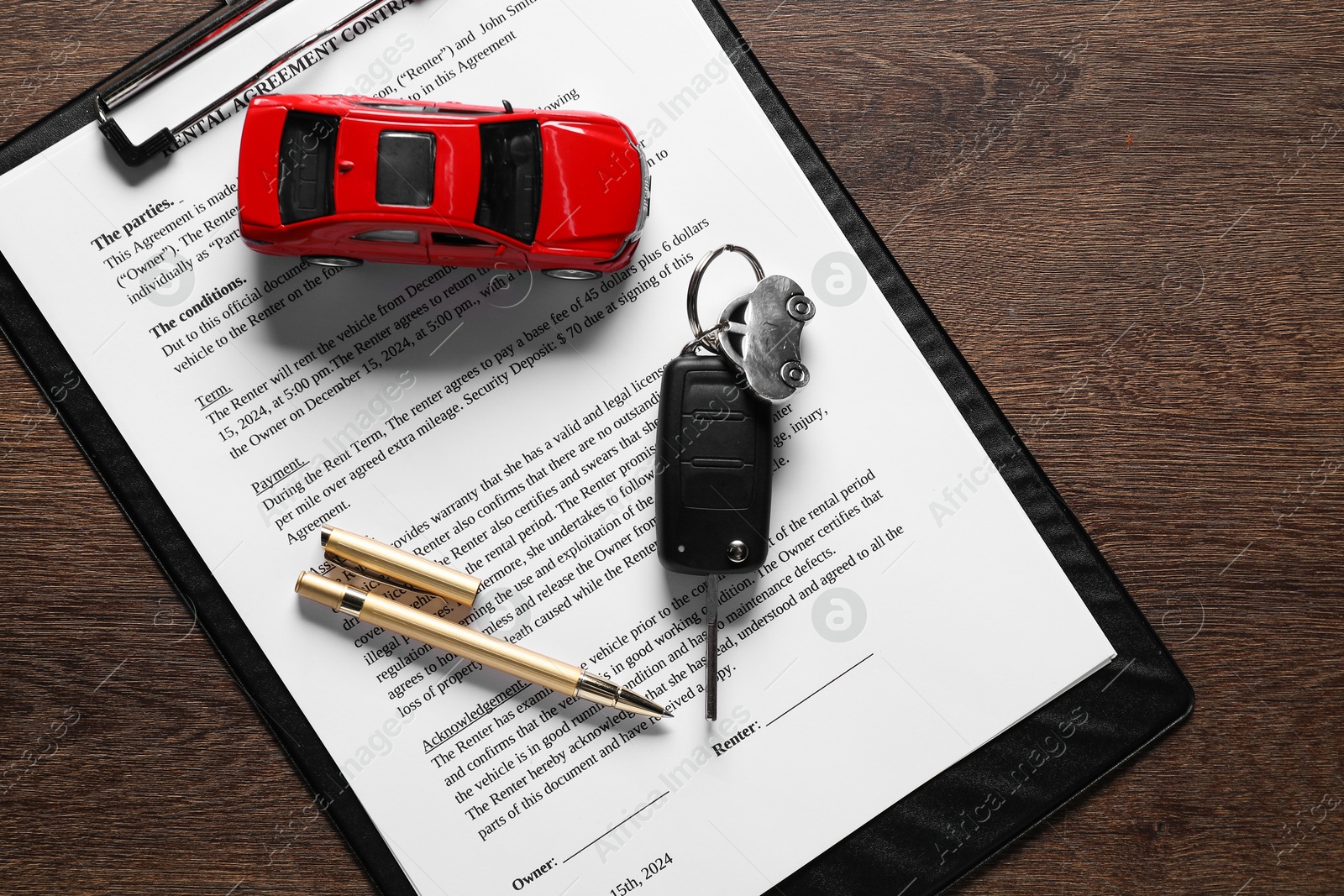 Photo of Car key, model and purchase agreement on wooden table, top view. Buying auto