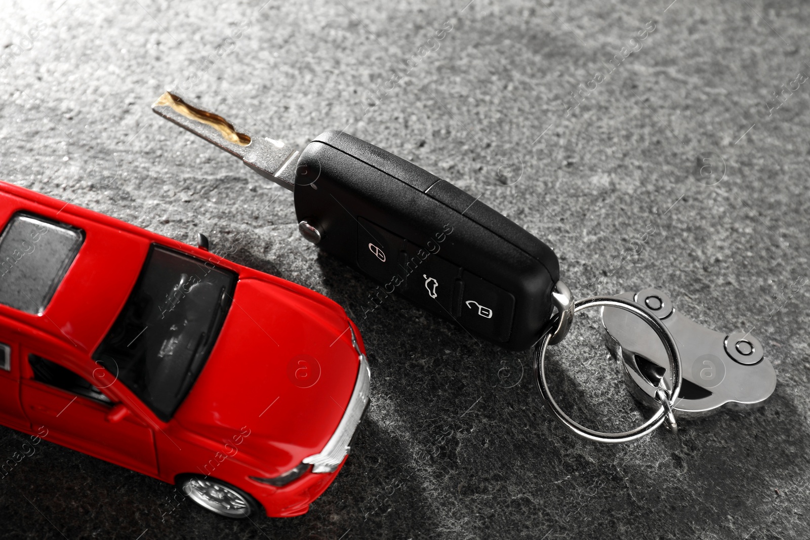 Photo of Car key and model on grey textured table, closeup. Buying auto