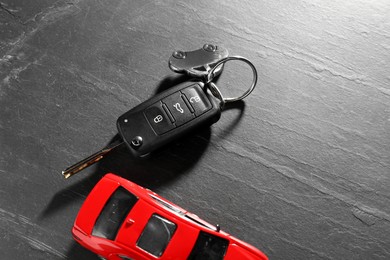 Photo of Car key and model on grey background, closeup. Buying auto