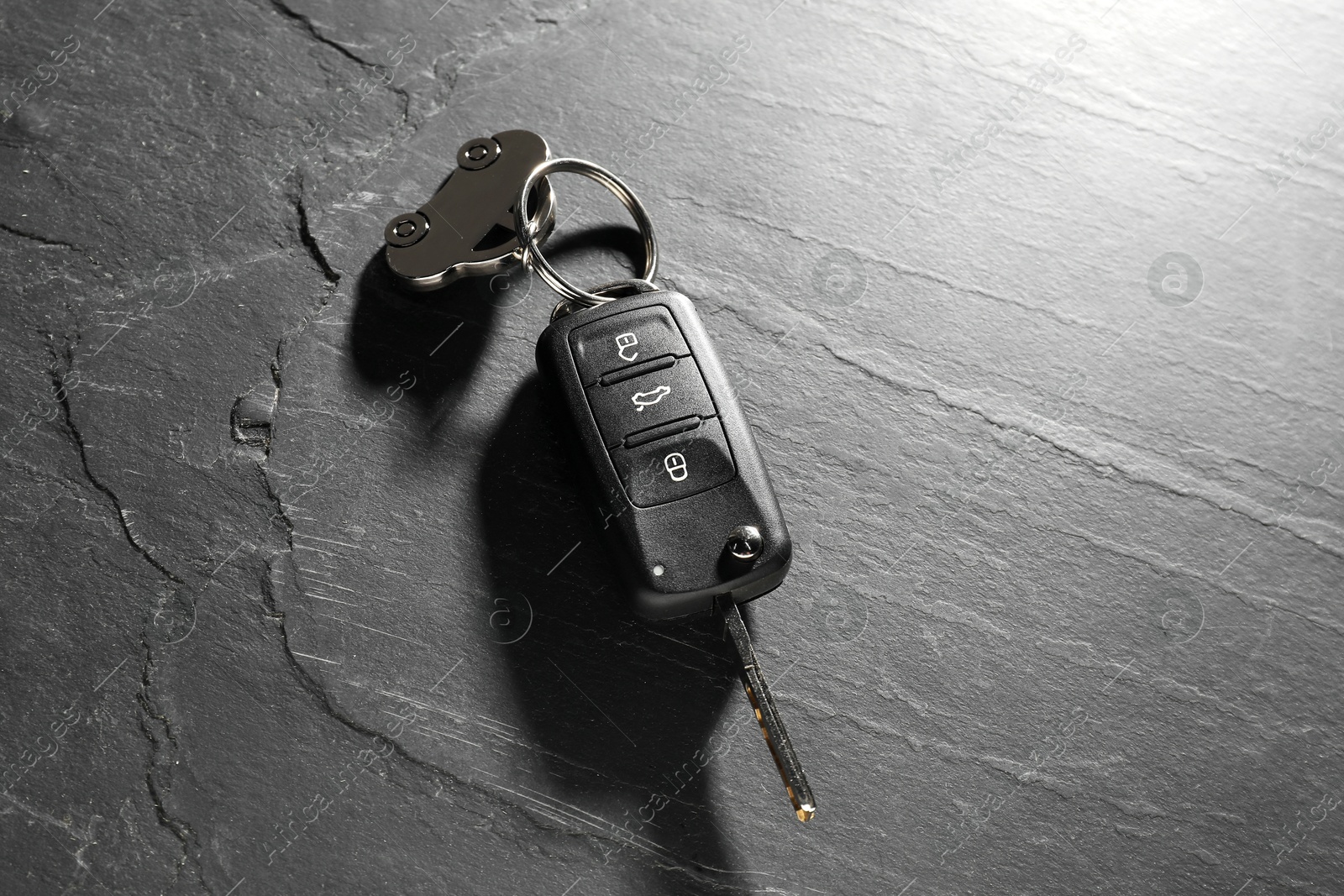 Photo of Car key with keychain on grey background, closeup. Buying auto