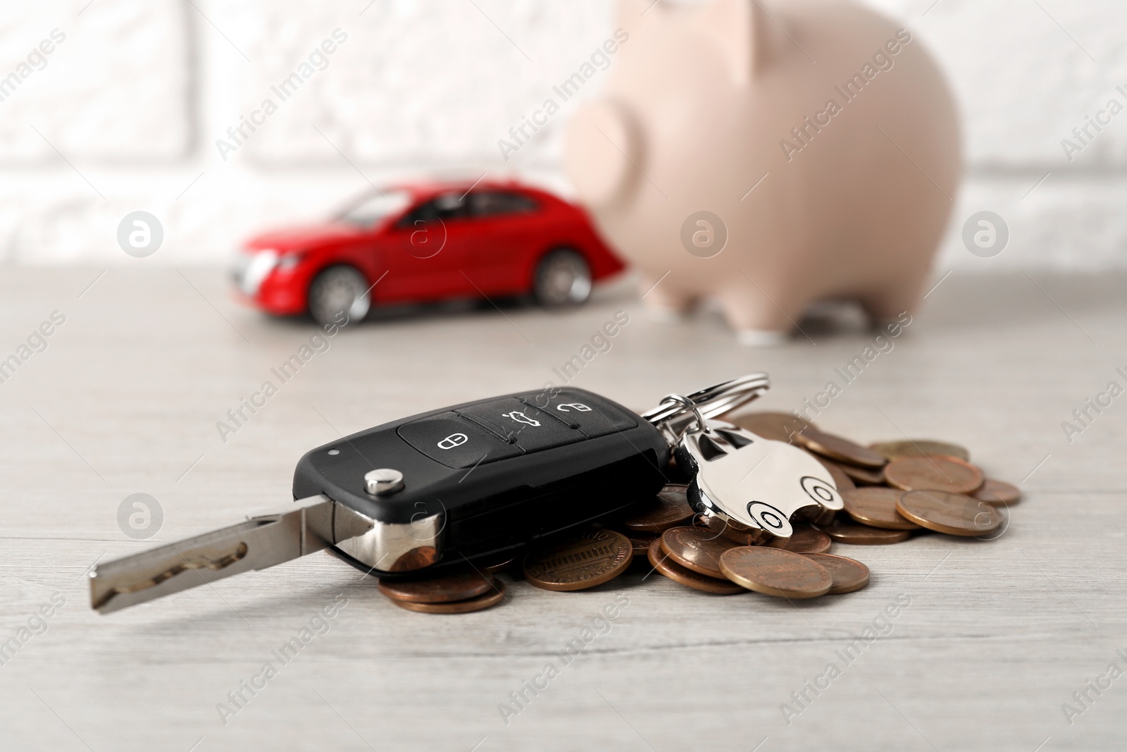 Photo of Car key and coins on light wooden table, closeup. Buying auto