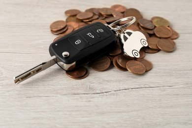 Photo of Car key and coins on light wooden table, closeup. Buying auto