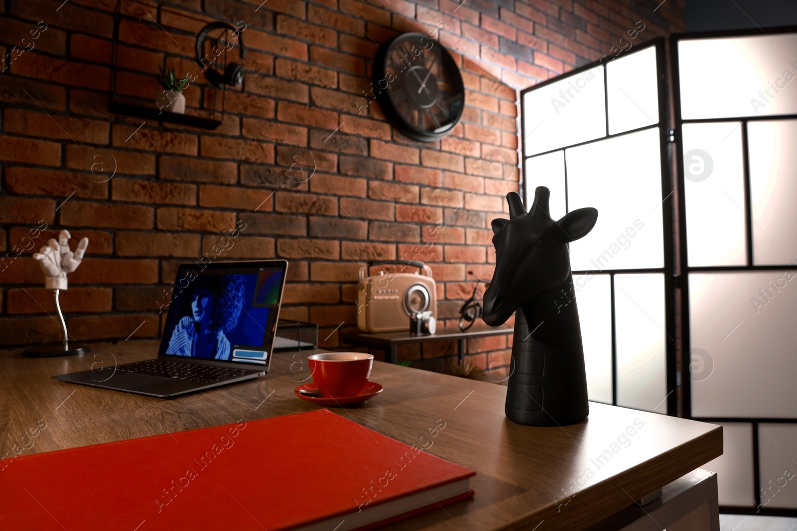 Photo of Book, laptop, cup of coffee and decor on wooden table near brick wall