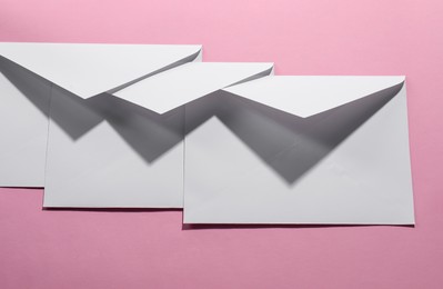 Photo of Paper envelopes on pink background, above view. Mockup for design