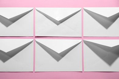 Photo of Paper envelopes on pink background, above view. Mockup for design