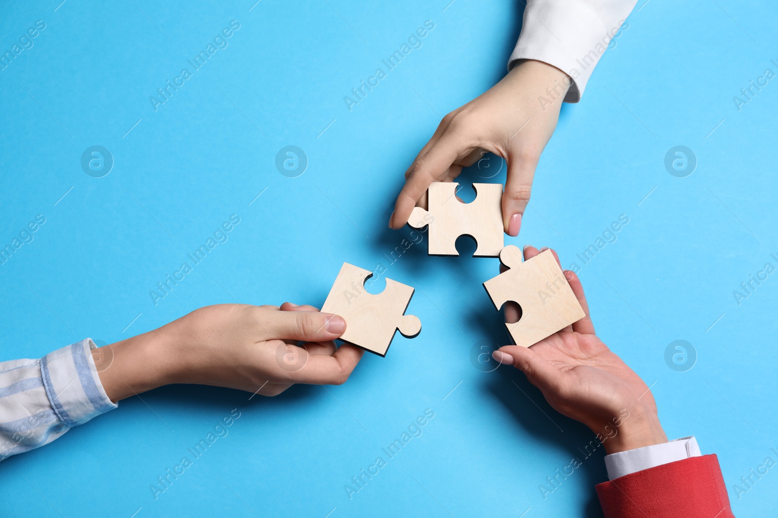 Photo of Business strategy and teamwork concept. Partners with different puzzle pieces on light blue background, top view