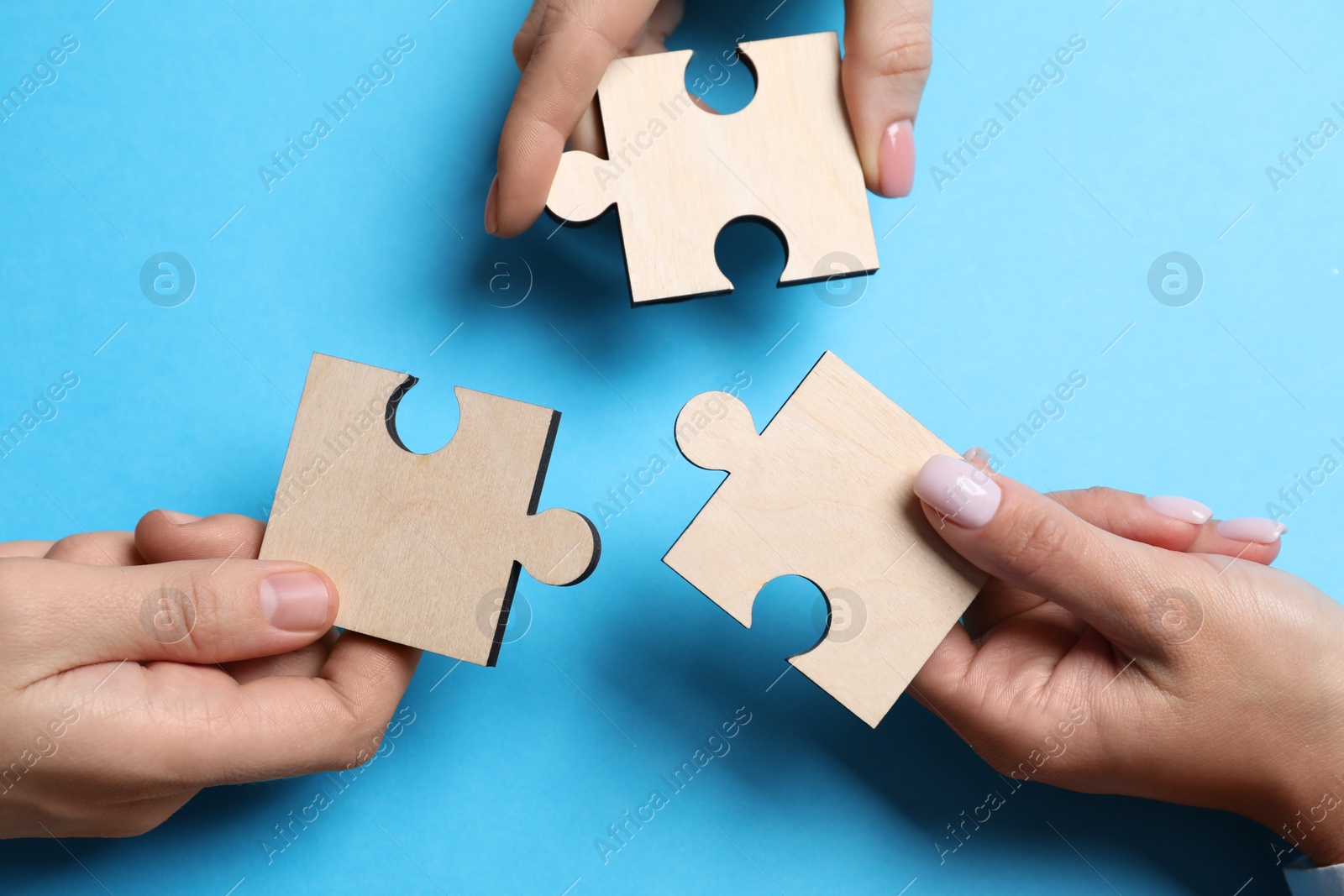 Photo of Business strategy and teamwork concept. Partners with different puzzle pieces on light blue background, top view