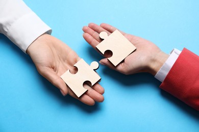 Photo of Business strategy and teamwork concept. Partners putting puzzle pieces together on light blue background, above view