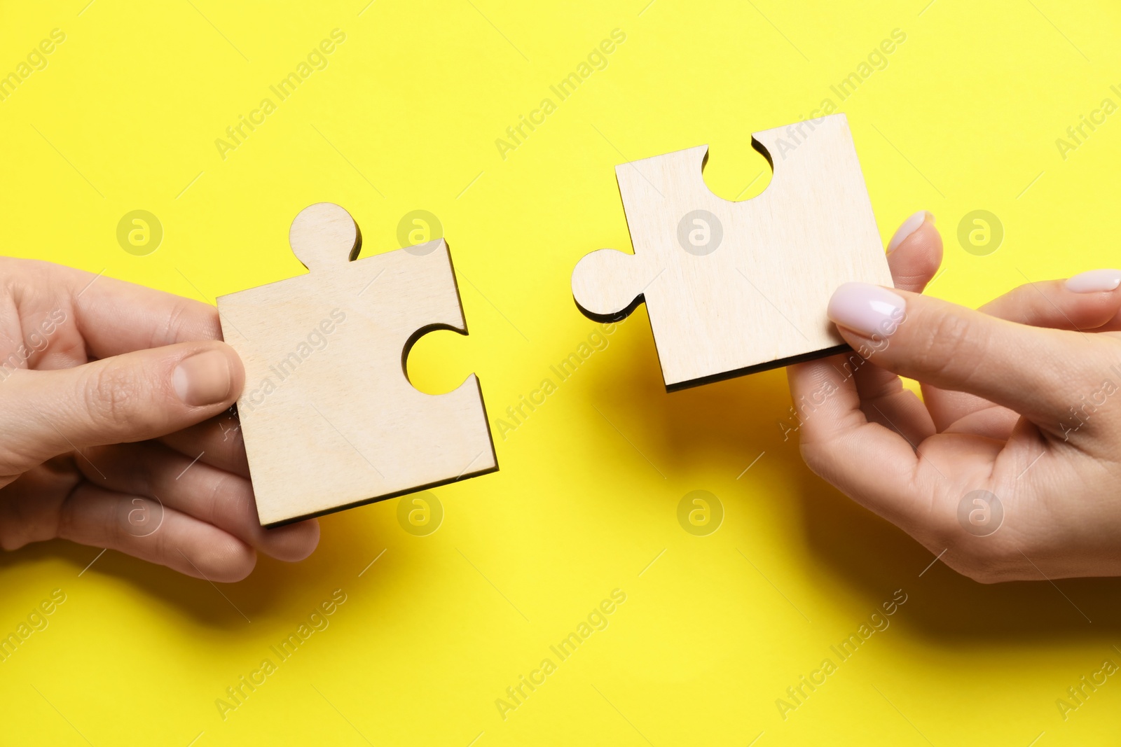 Photo of Business strategy and teamwork concept. Partners putting puzzle pieces together on yellow background, closeup