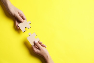 Photo of Business strategy and teamwork concept. Partners putting puzzle pieces together on yellow background, top view with space for text