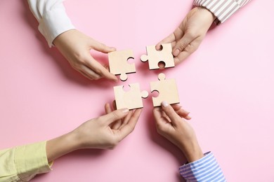 Photo of Business strategy and teamwork concept. Group of businesspeople putting puzzle pieces together on pink background, top view