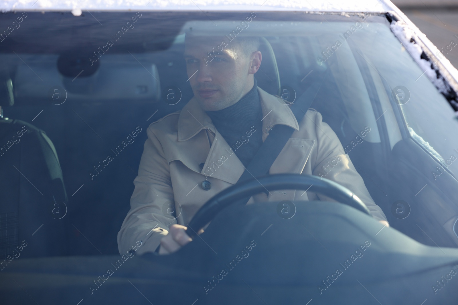 Photo of Driver behind steering wheel of modern car, view from windshield