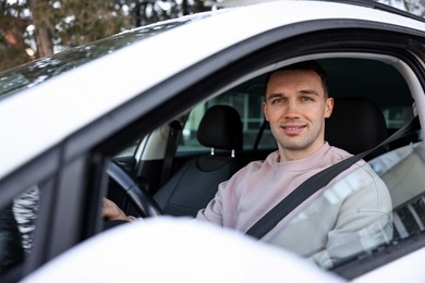 Photo of Driver behind steering wheel of modern car, view from outside