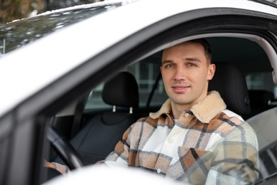 Photo of Driver behind steering wheel of modern car, view from outside