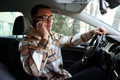 Photo of Driver talking on smartphone while driving modern car