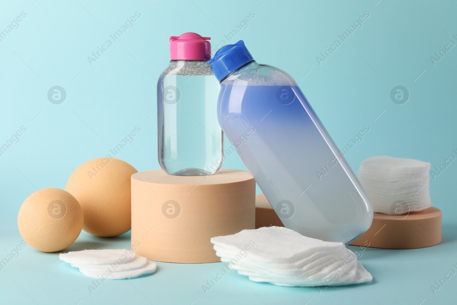 Photo of Clean cotton pads and micellar water on light blue background