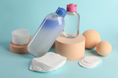 Photo of Clean cotton pads and micellar water on light blue background