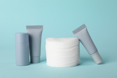 Photo of Clean cotton pads and cosmetic products on light blue background