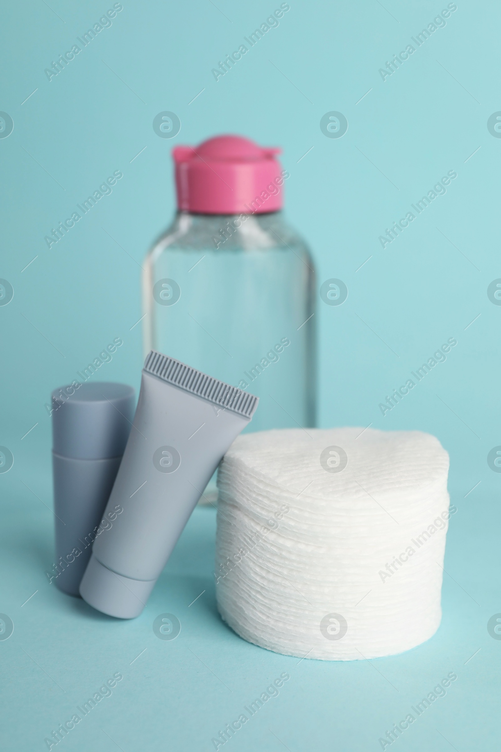 Photo of Clean cotton pads and cosmetic products on light blue background