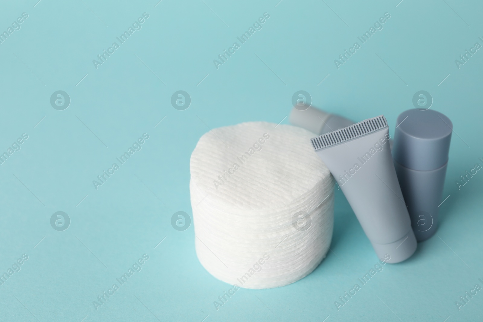 Photo of Clean cotton pads and cosmetic products on light blue background, closeup. Space for text