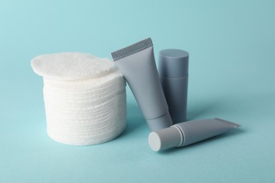 Photo of Clean cotton pads and cosmetic products on light blue background, closeup