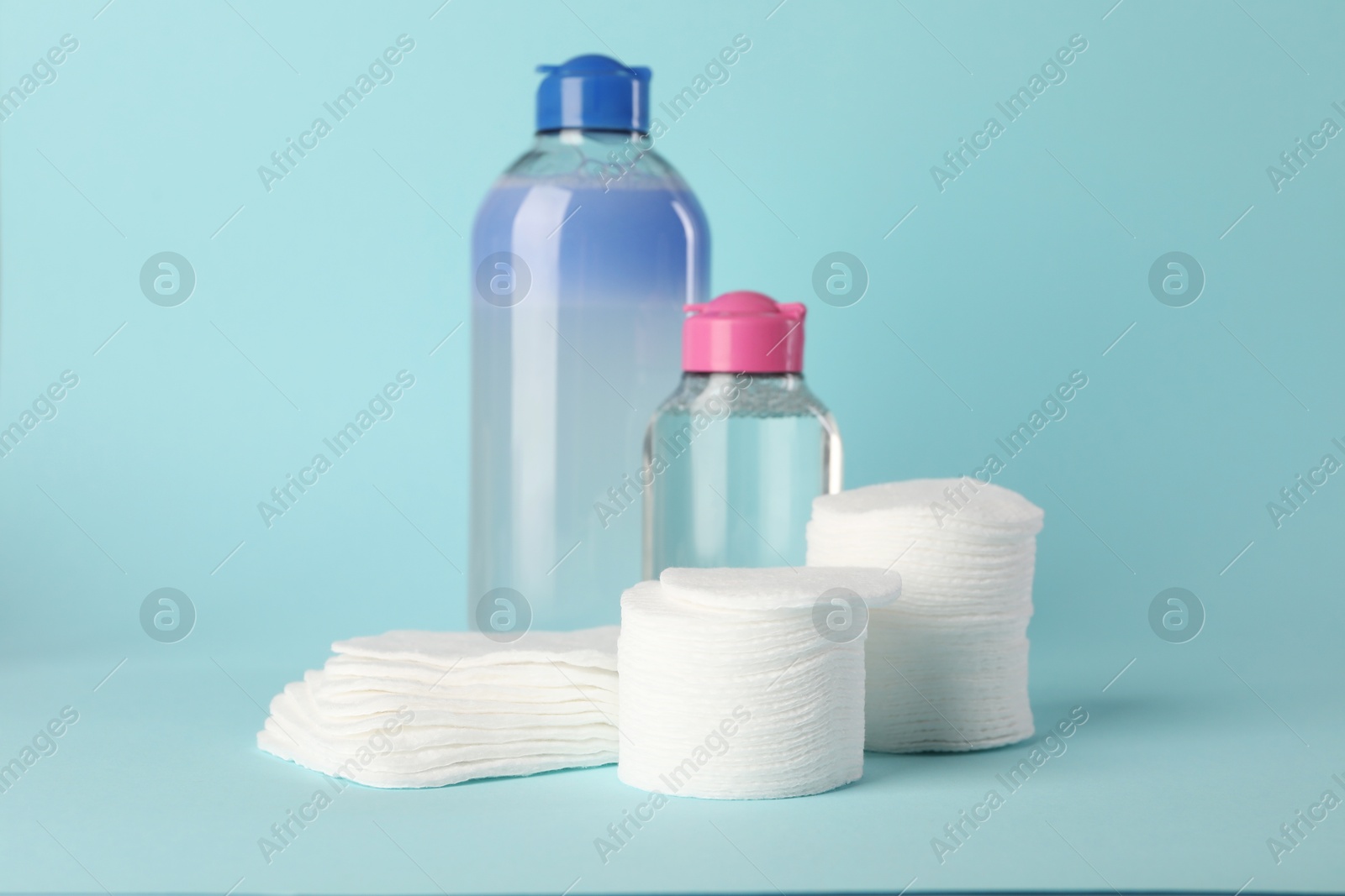 Photo of Clean cotton pads and micellar water on light blue background