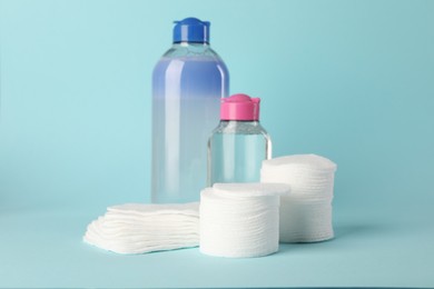 Photo of Clean cotton pads and micellar water on light blue background