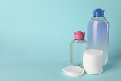 Photo of Clean cotton pads and micellar water on light blue background. Space for text