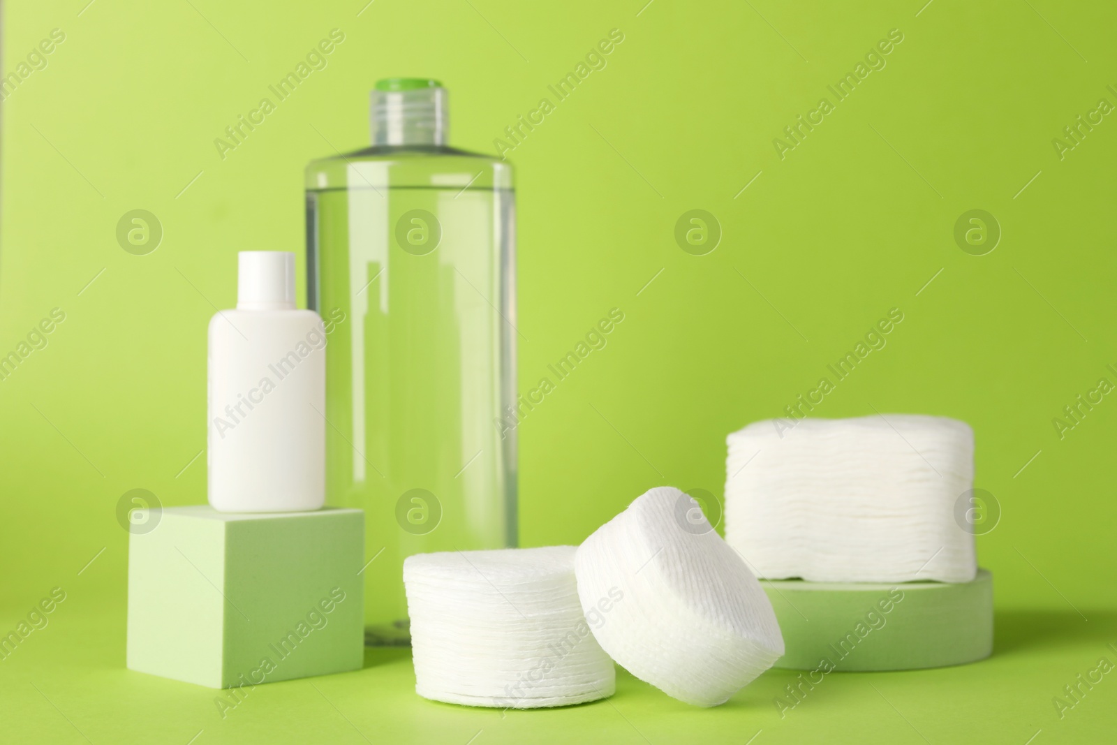 Photo of Clean cotton pads and cosmetic products on green background. Space for text