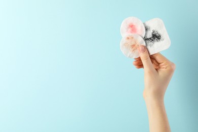 Photo of Woman with dirty cotton pads on light blue background, closeup. Space for text