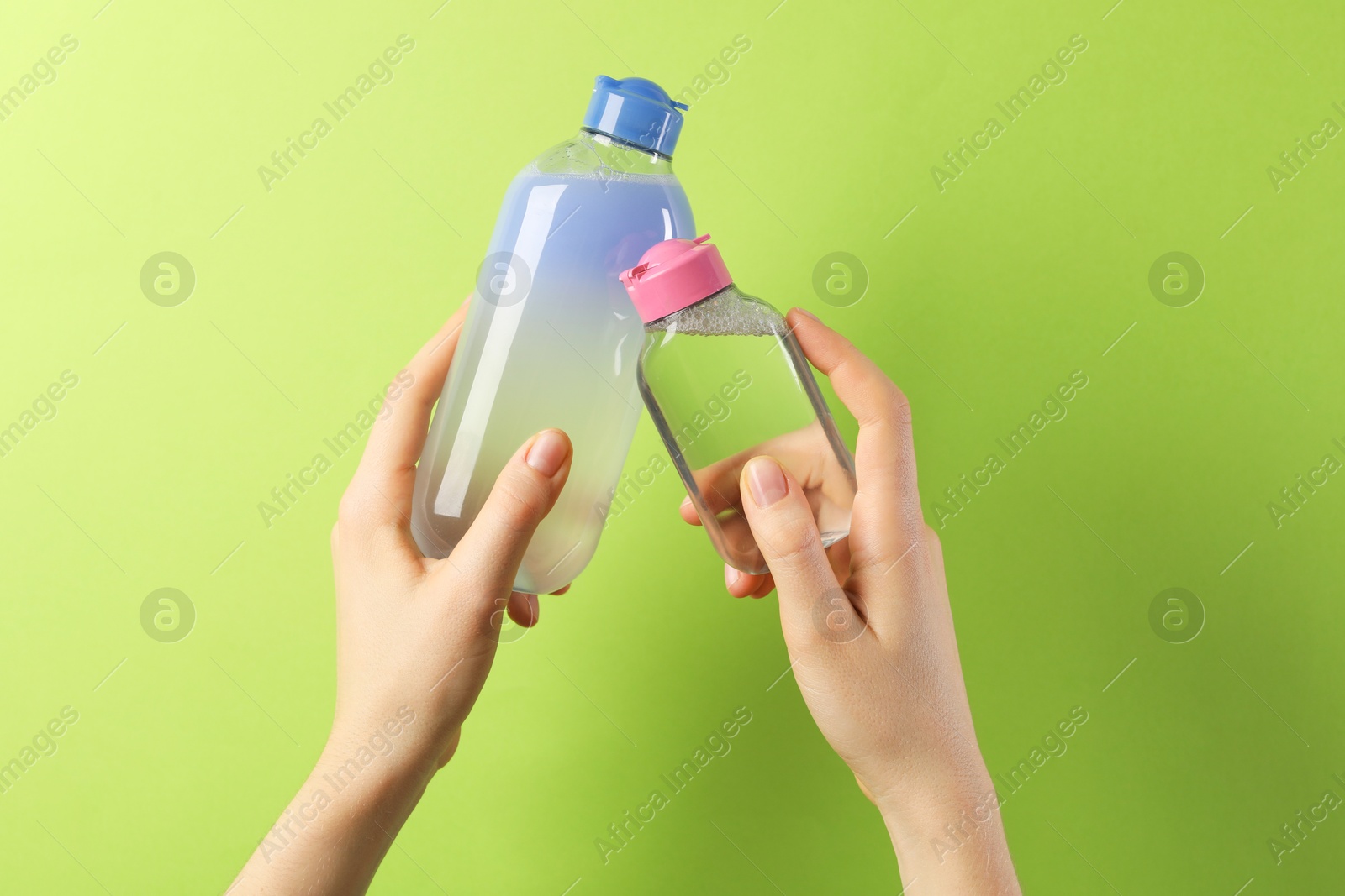 Photo of Woman with bottles of cosmetic products on green background, closeup