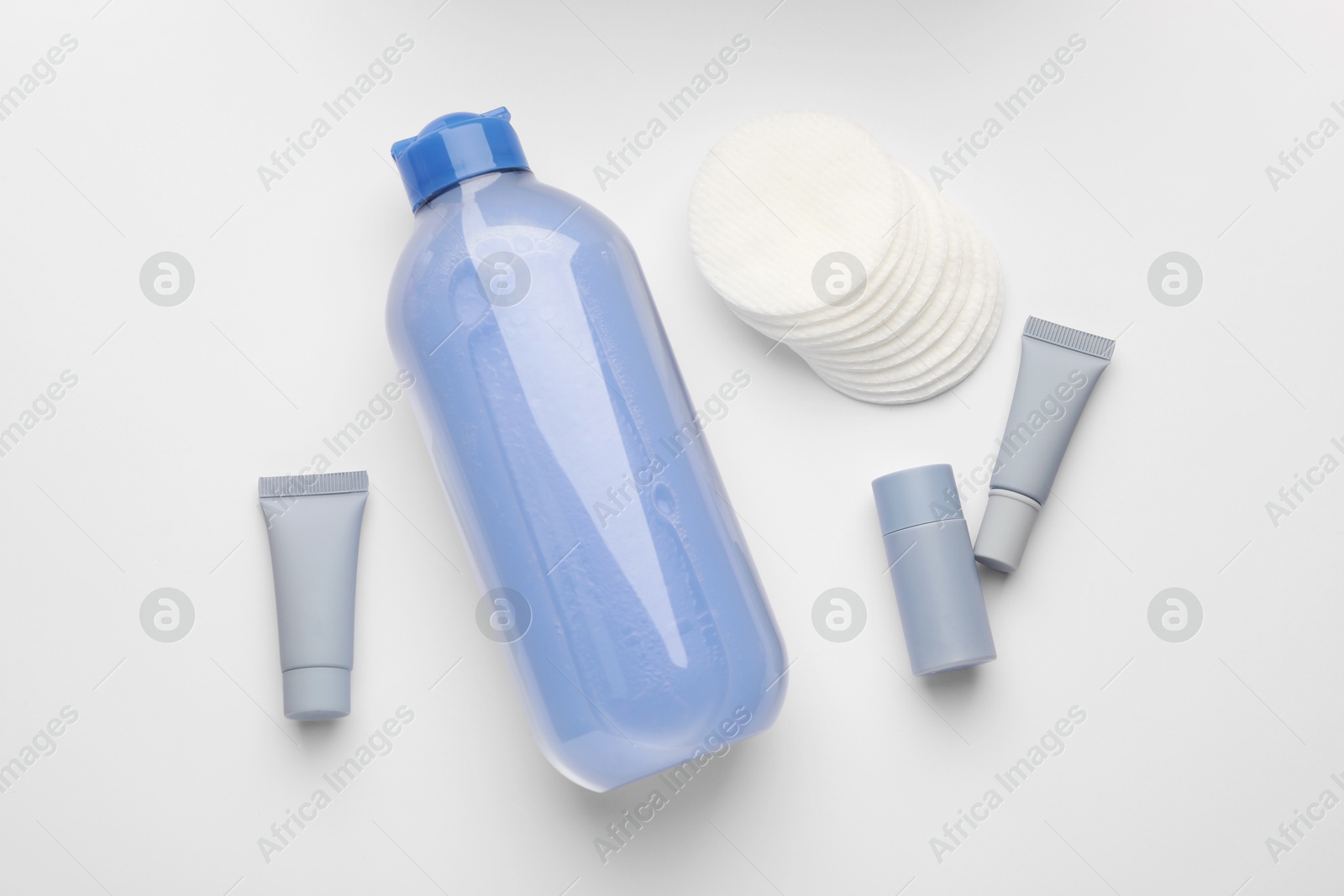 Photo of Clean cotton pads and cosmetic products on white background, flat lay