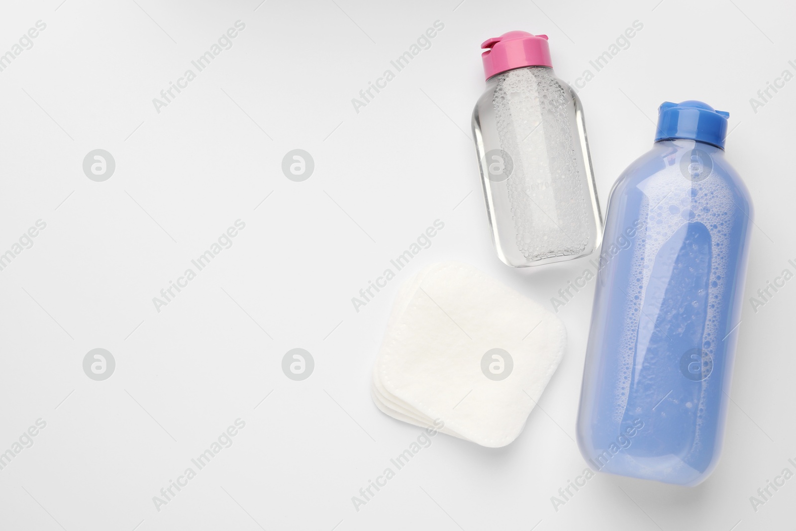 Photo of Clean cotton pads and micellar water on white background, flat lay. Space for text