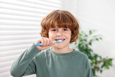 Photo of Cute boy brushing his teeth at home