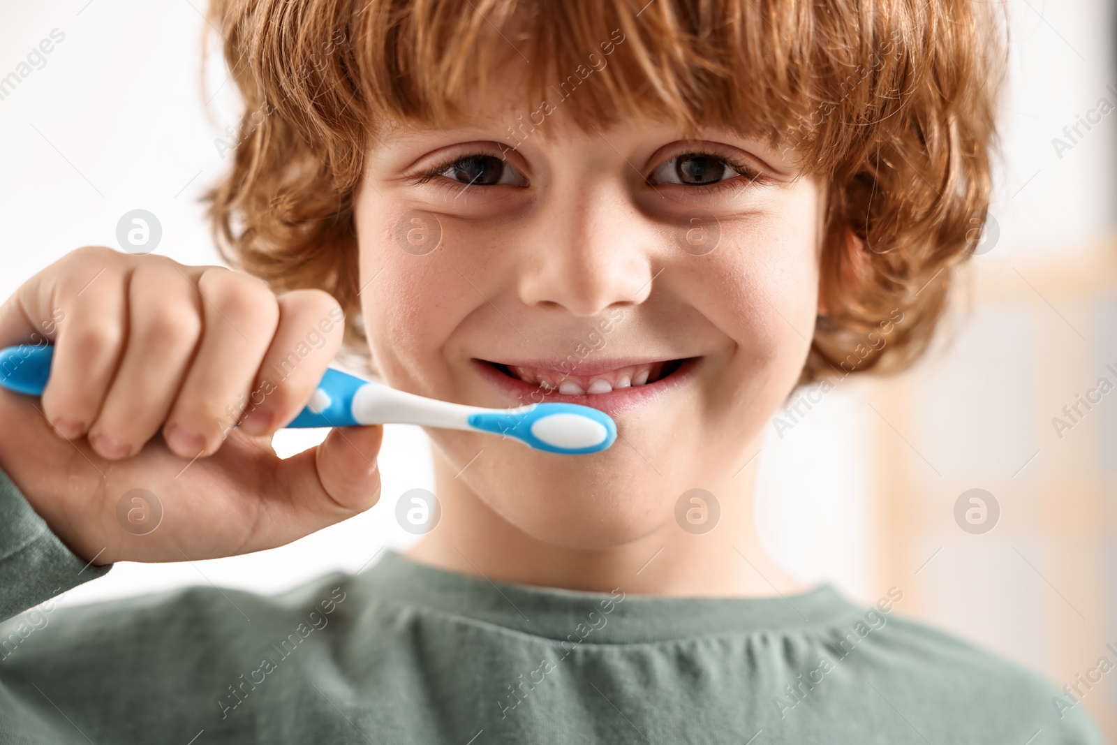 Photo of Cute boy brushing his teeth indoors, closeup