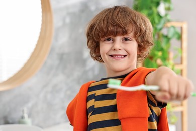 Photo of Cute boy with toothbrush in bathroom, selective focus