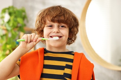 Photo of Cute boy brushing his teeth at home