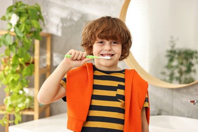 Photo of Cute boy brushing his teeth in bathroom