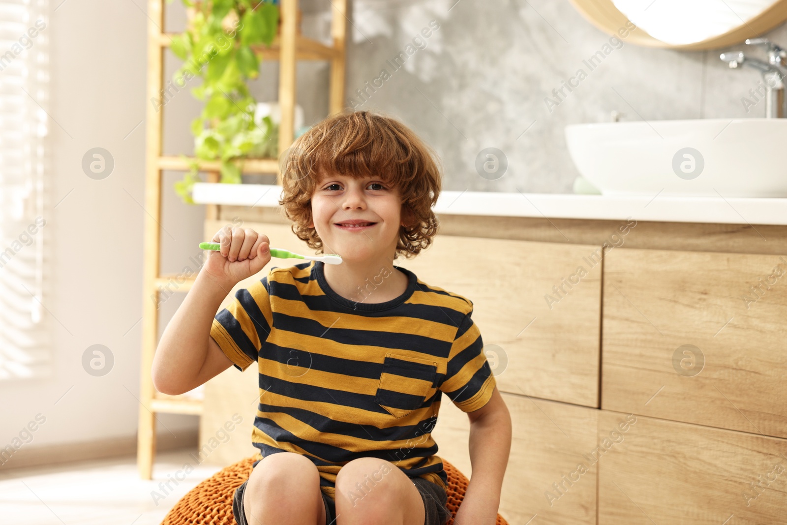 Photo of Cute boy brushing his teeth in bathroom