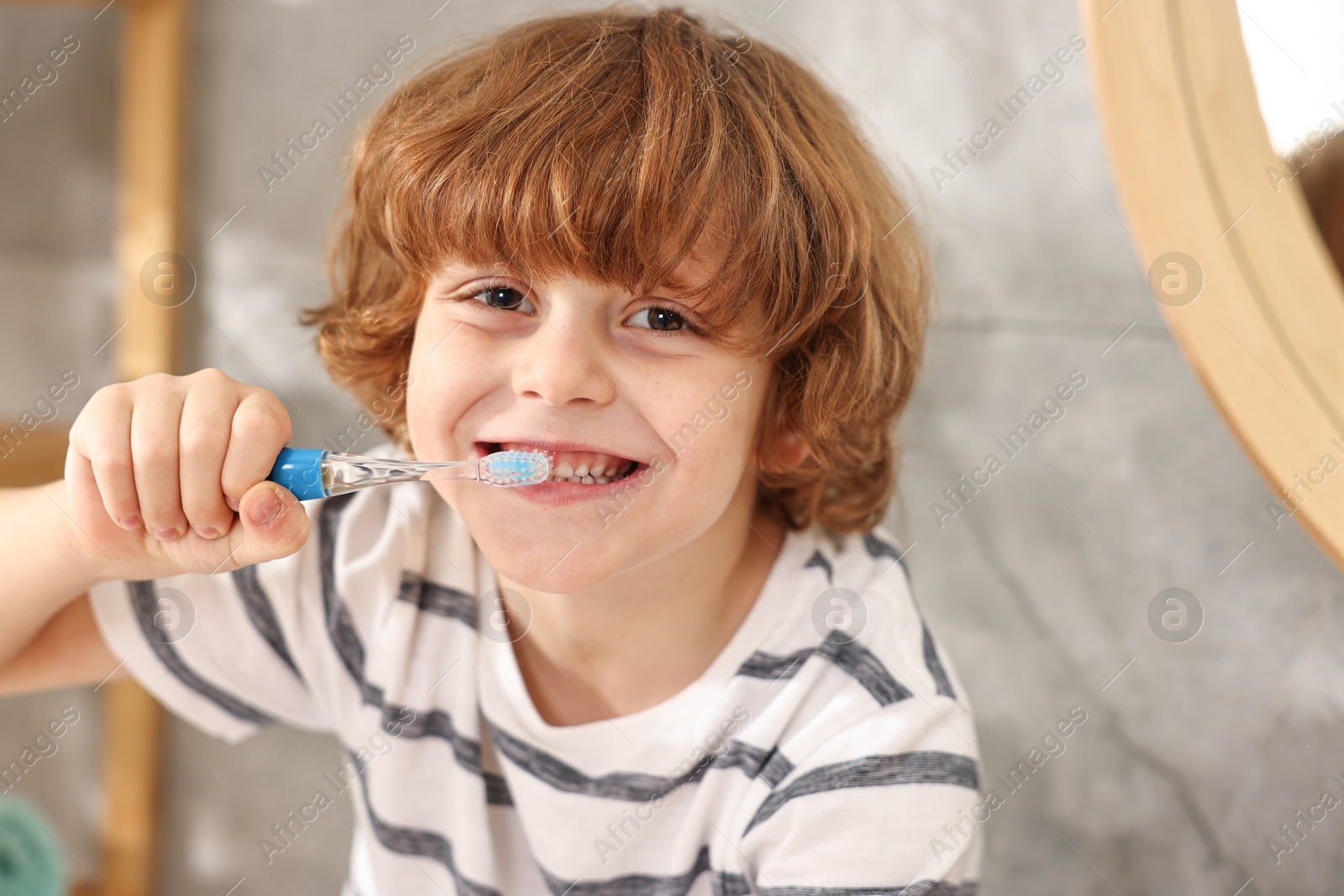 Photo of Cute boy brushing his teeth in bathroom