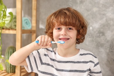 Photo of Cute boy brushing his teeth in bathroom