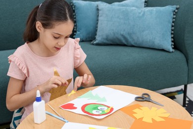 Photo of Girl making art project at table indoors