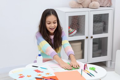 Photo of Girl making art project at table indoors