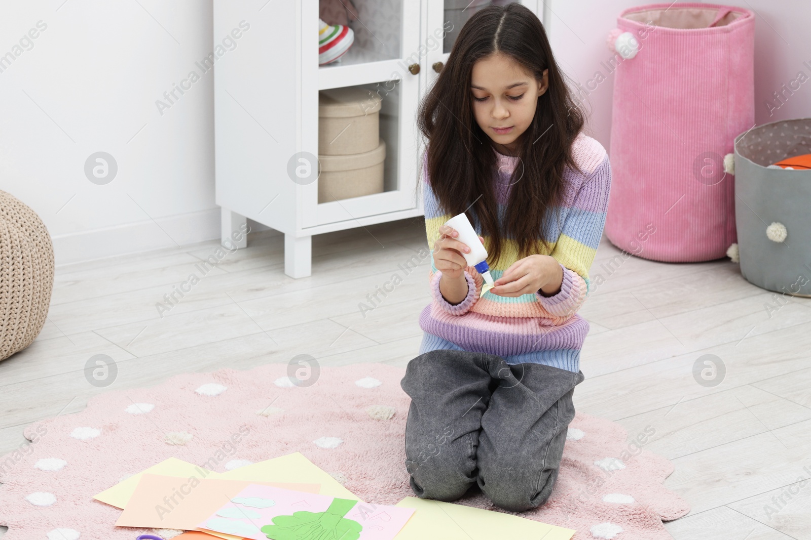 Photo of Girl applying glue onto paper figure for her creative project indoors, space for text. Art and craft