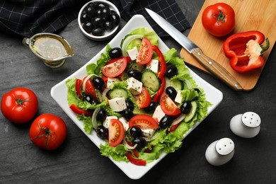 Photo of Delicious fresh Greek salad on black table, flat lay