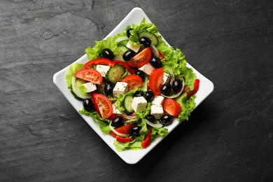 Photo of Delicious fresh Greek salad on black table, top view