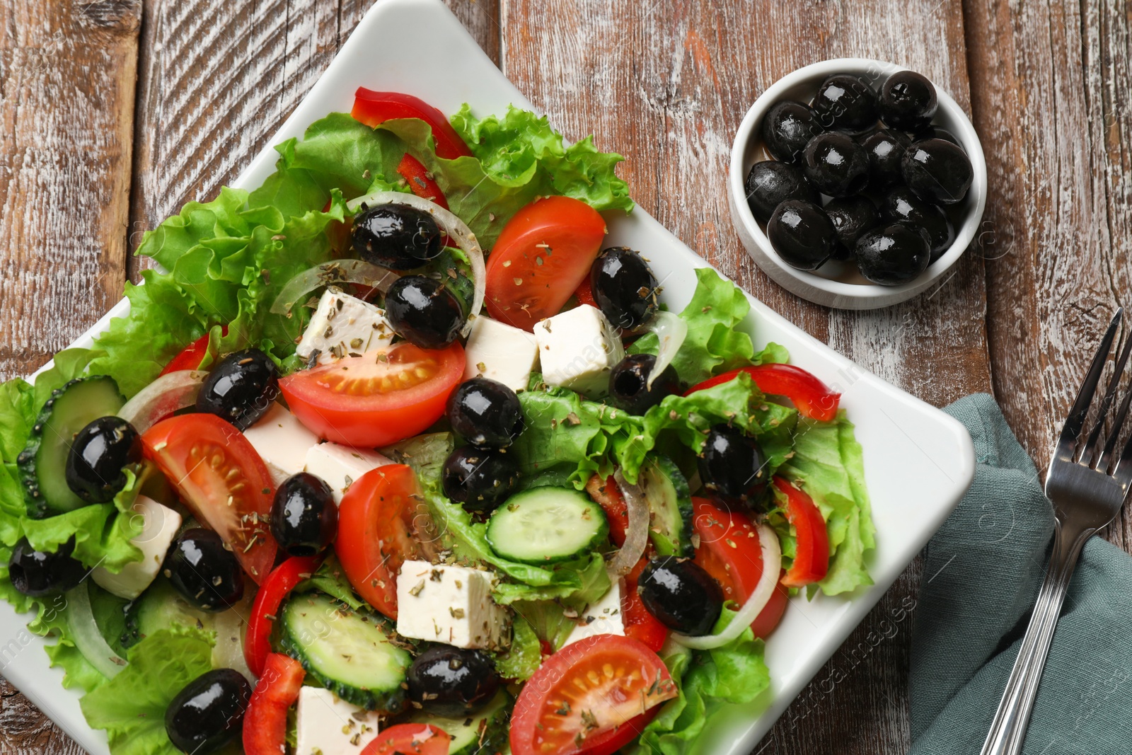 Photo of Delicious fresh Greek salad on wooden table, top view