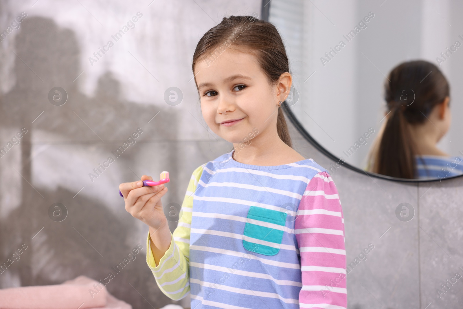 Photo of Cute girl with toothbrush in bathroom. Personal hygiene