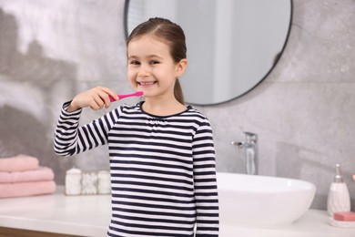 Photo of Cute girl brushing her teeth in bathroom