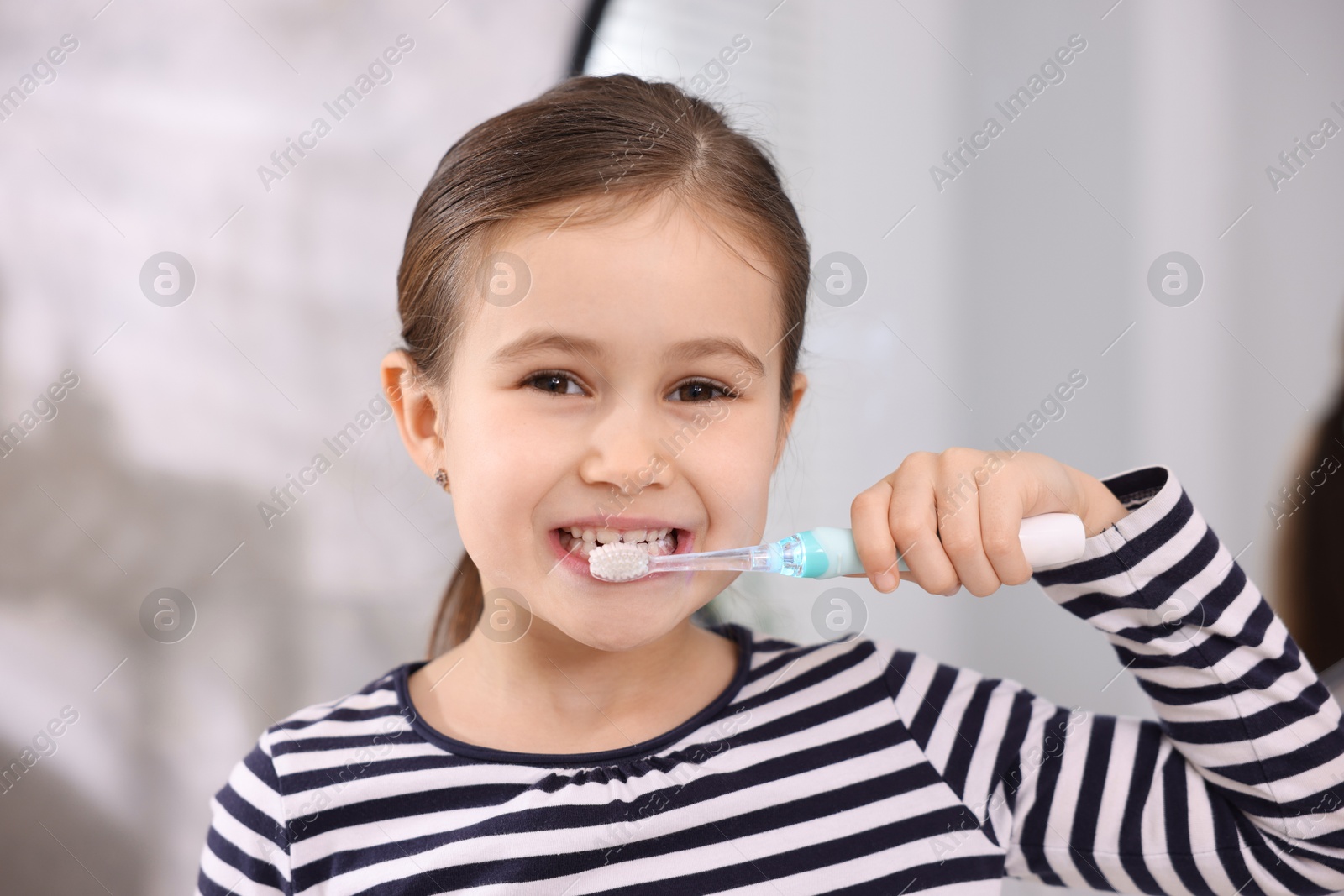 Photo of Cute girl brushing her teeth in bathroom